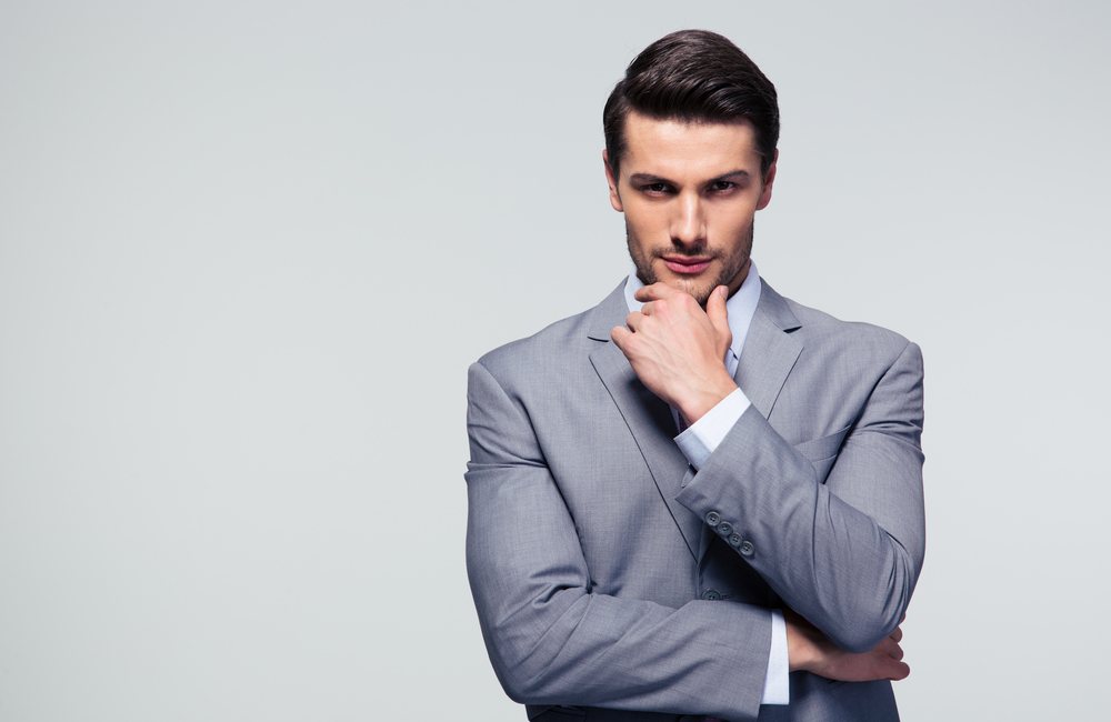 Portrait of a pensive businessman touching his chin over gray background