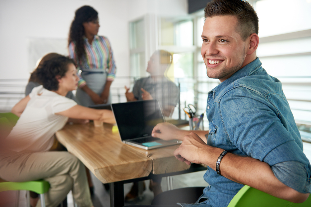 Image of a succesful casual business man using laptop during meeting